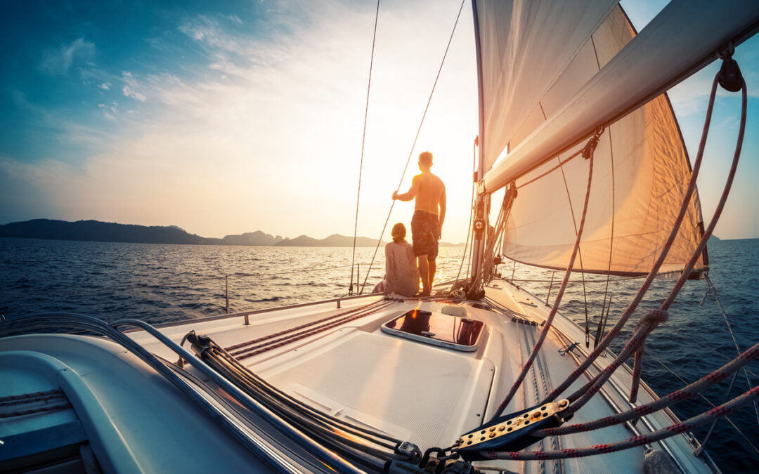 Couple enjoying sunset from the deck of the sailing boat moving in a sea - boat insurance