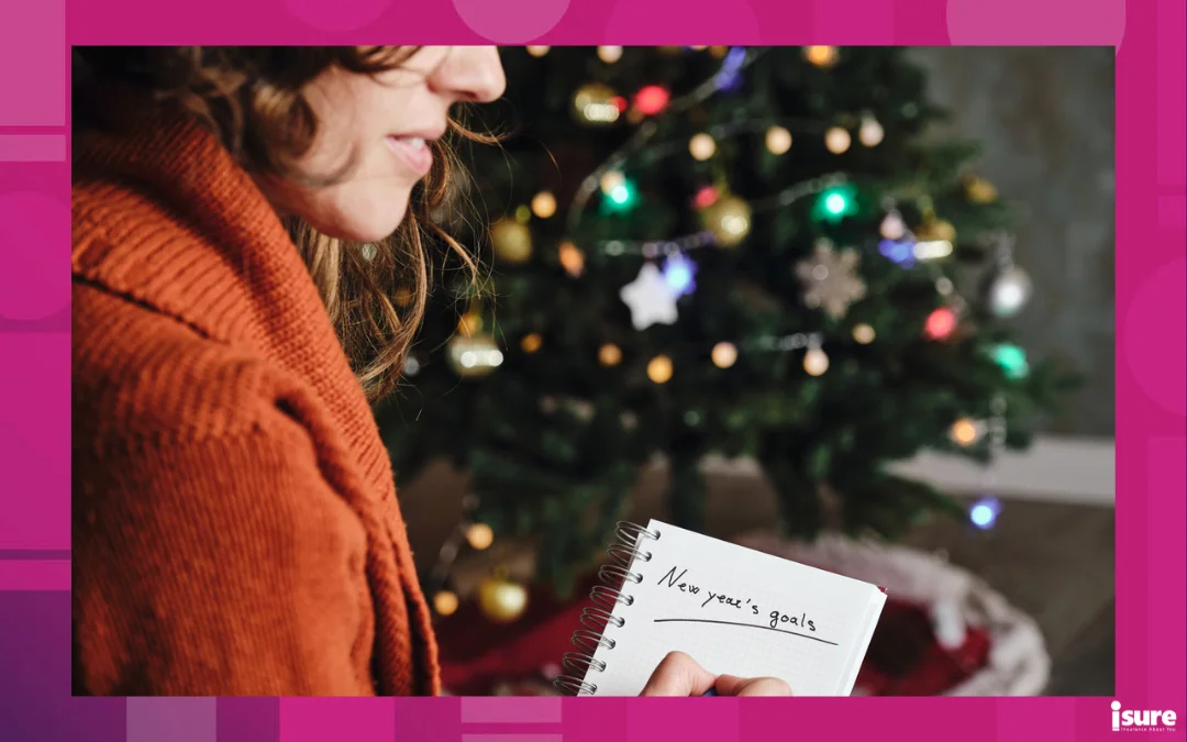 new year's resolutions - Caucasian woman smiling with orange sweater in profile with new year's goals notebook in hand with unfocused christmas tree in the background