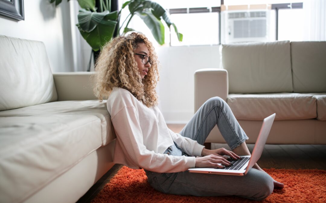 young woman sitting on the floor with her laptop at home - staying safe online while working from home