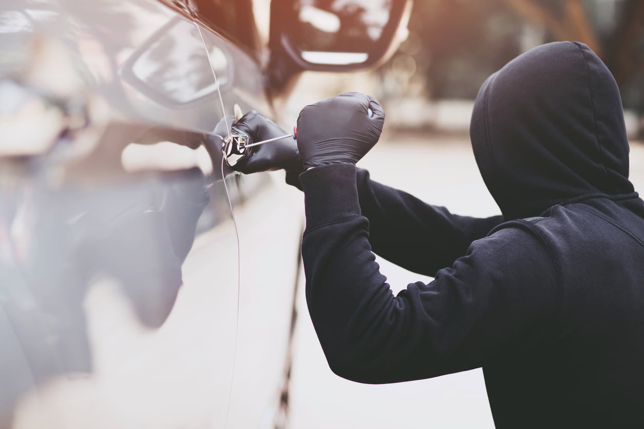 A thief is attempting to break into a vehicle through the side door - GAP insurance