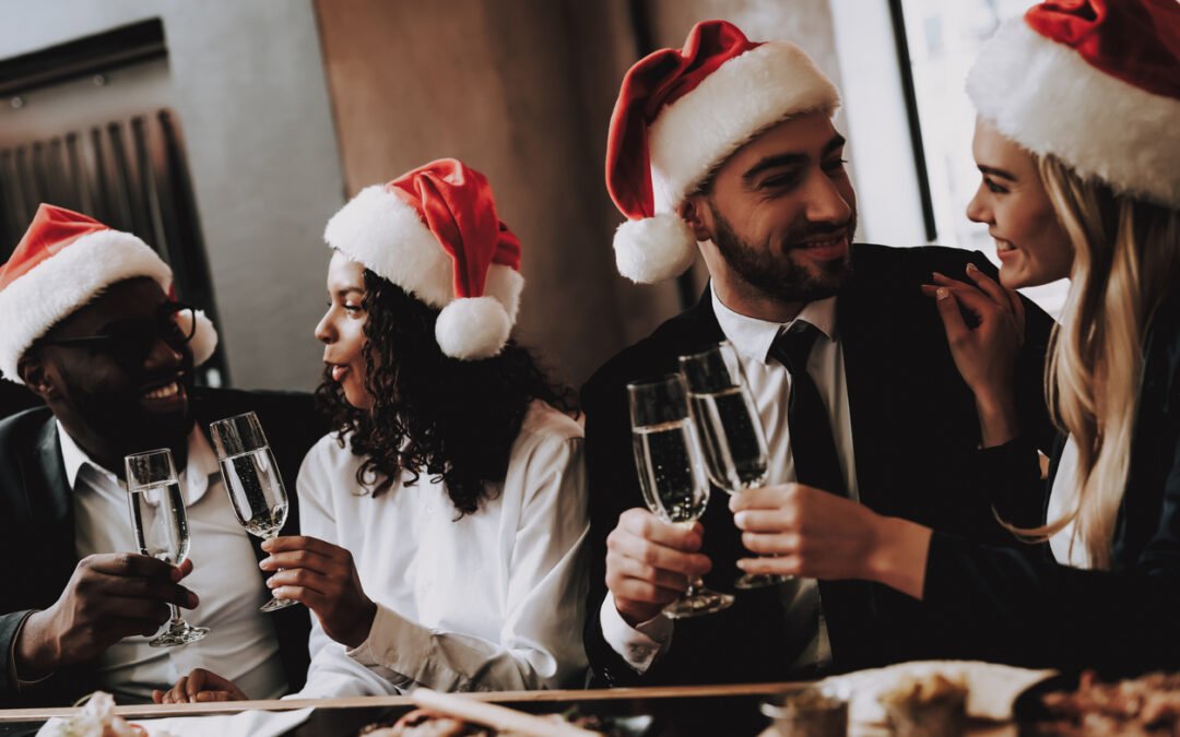 Santa's Hat. two multi-racial couples wearing santa hats toast to Christmas with champagne. How the holidays may affect your home insurance