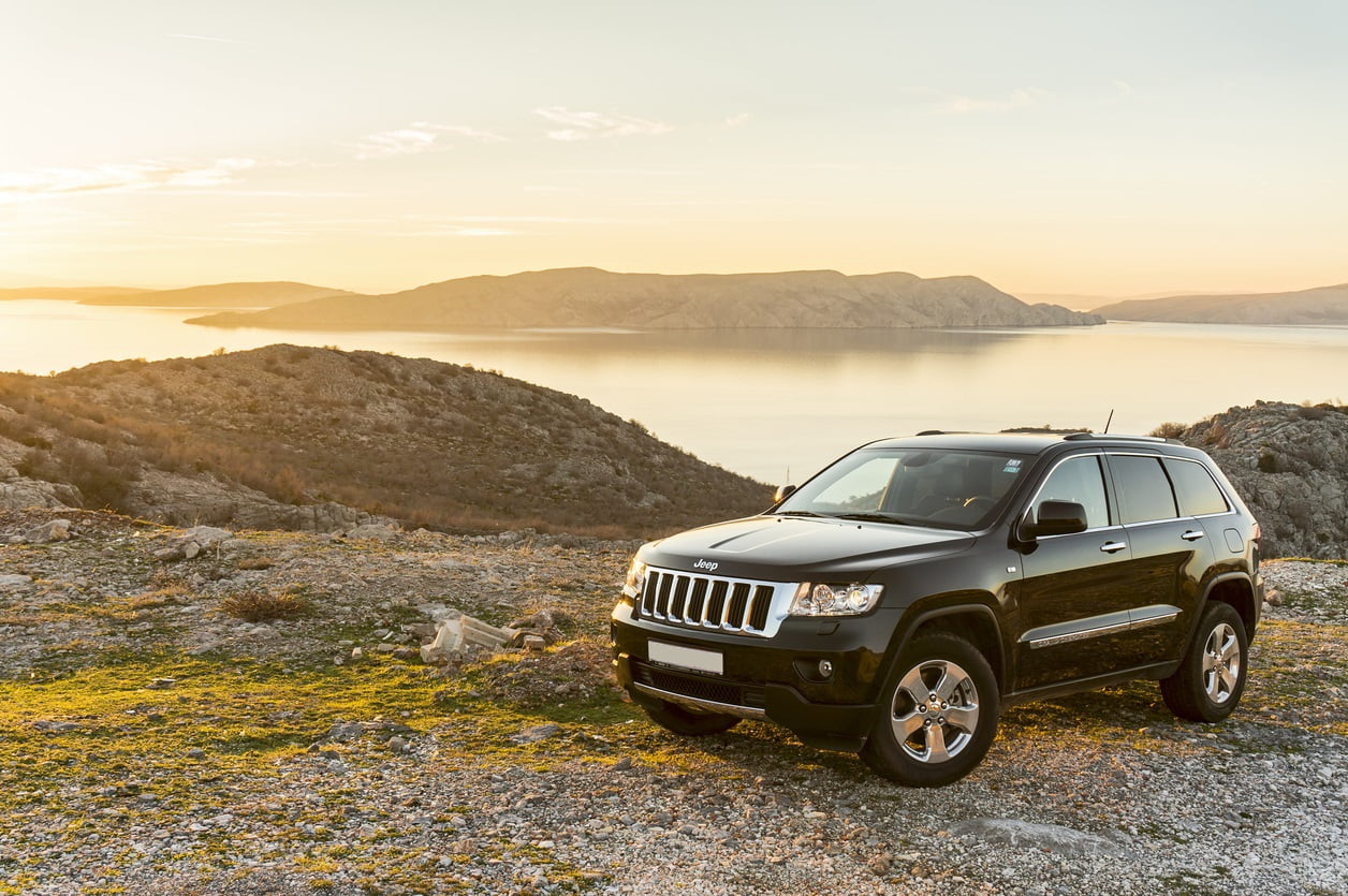 Zagreb, Croatia - December 30, 2012: Jeep Grand Cherokee 3.0 TDI parked at the sunset on hill with beautiful seashore and islands of Adriatic sea in the background. - top suvs and crossovers for 2022
