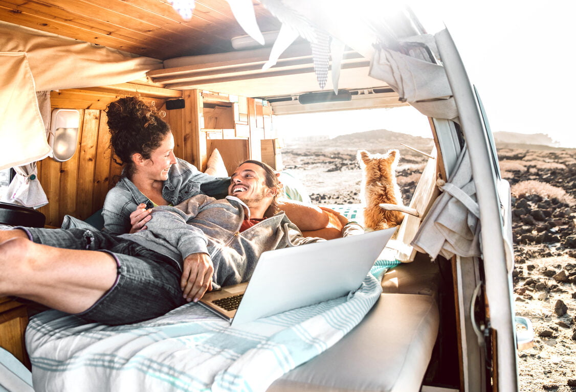 Hipster couple with dog traveling together on generic mini van transport - Digital nomad concept with indie people on minivan romantic trip working at laptop pc in relax moment, RV insurance