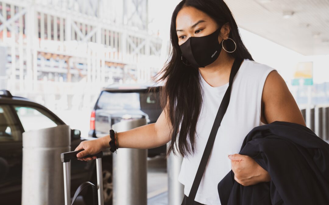 masked woman going through the airport - travel and COVID-19