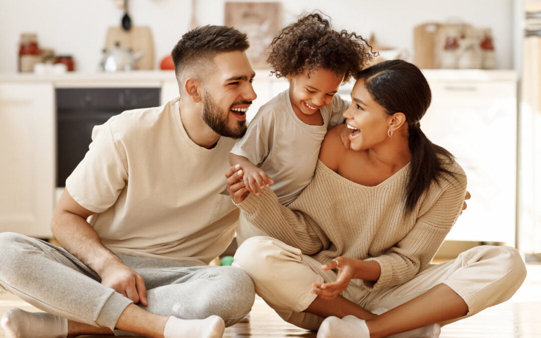 happy family multiethnic mother, father and son laughing, playing,and tickles on floor in cozy kitchen at home - life insurance policy