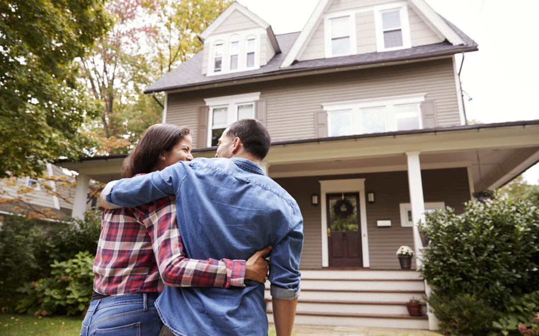 Rear view photo of couple and first-time home buyers walking towards their new home