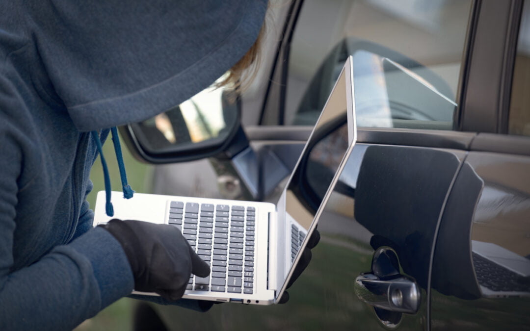 most stolen vehicles - Hooded thief tries to break the car's security systems with laptop. Hacking modern car concept