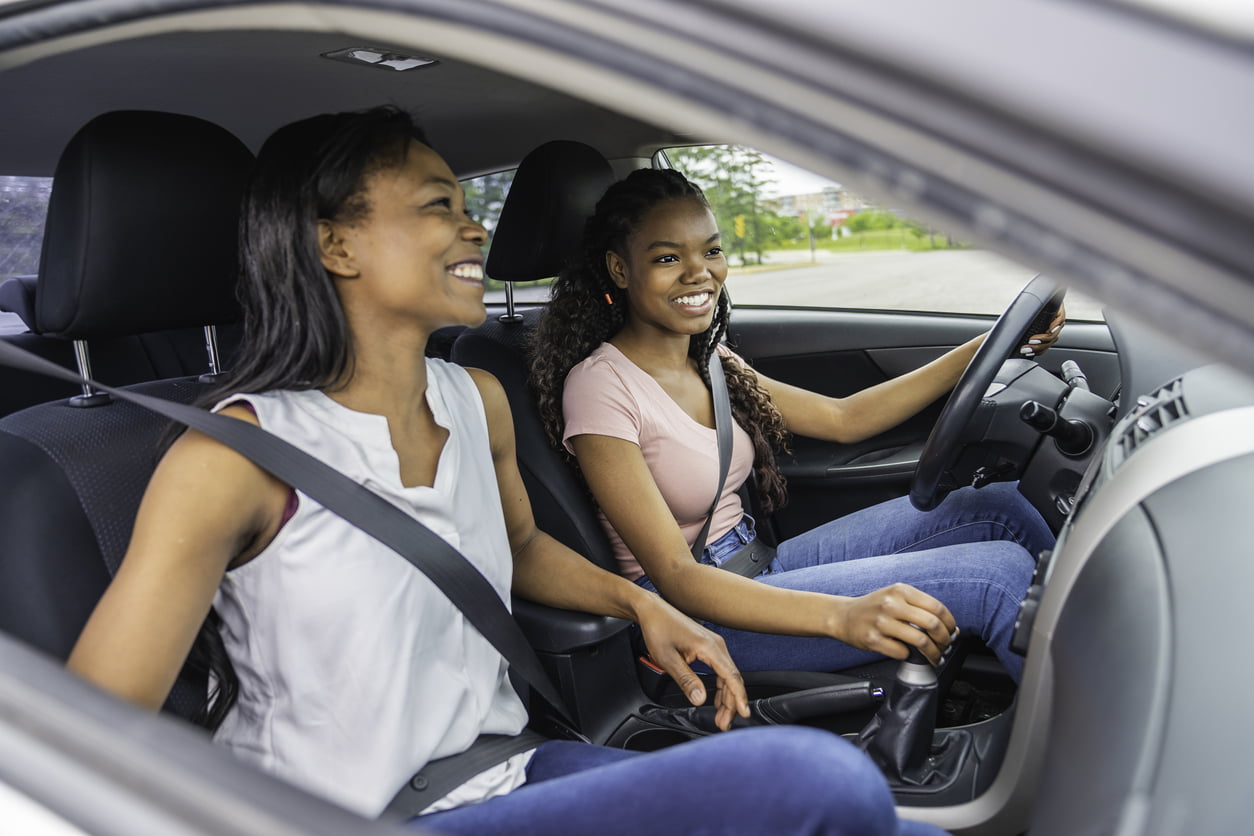 A Young black teenage driver seated in her new car with her mother - best cars for teen drivers