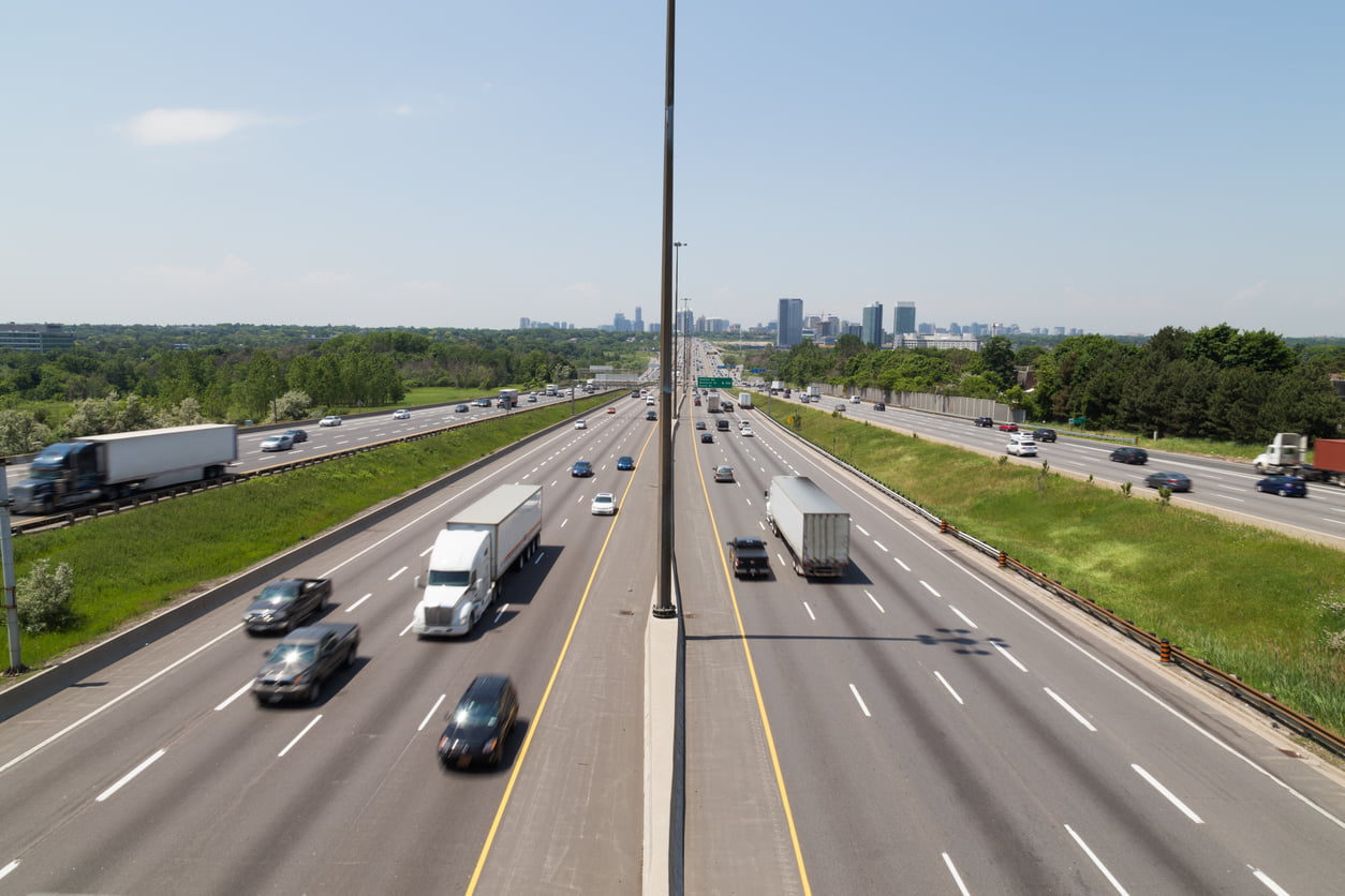 Part of Highway 401 in Toronto during the day showing the blur of traffic on the road - speed limit changes