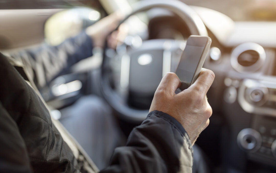 Affordable car insurance for high risk drivers - Using a phone in a car texting while driving concept for danger of text message and being distracted