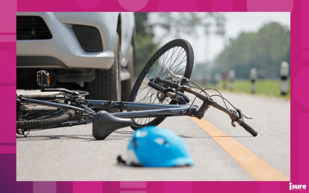 A photo of the shoulder of the road, with a bicycle turned on its side in front of a car, and a blue helmet on the ground just in front. Grey sky and green grass and forest line in the background.