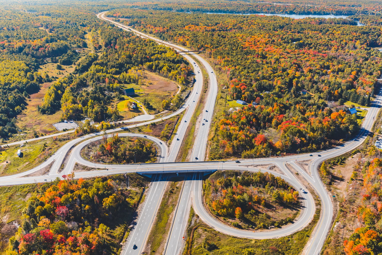 Ontario highway driving - Highway junction aerial view in autumn. Photo taken in Ontario, Canada, from the helicopter during fall season. Colourful trees and wood. Travel and nature concepts
