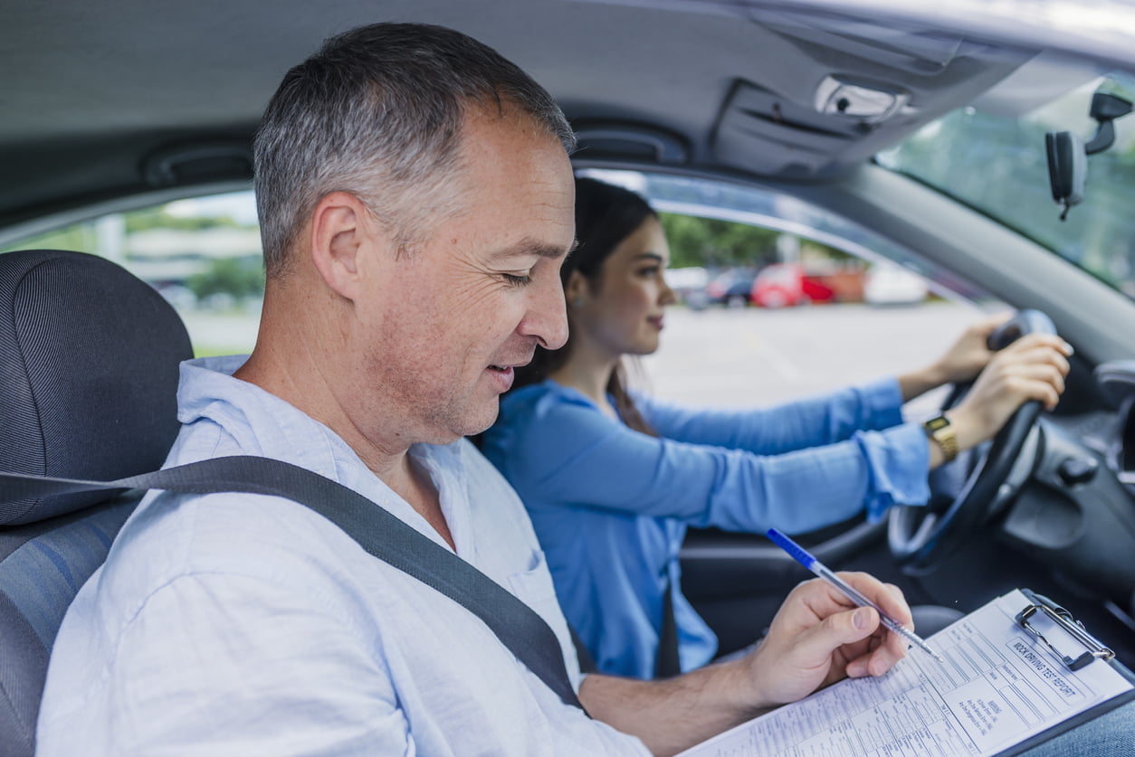 Young woman on a driving test with her instructor. Learning to drive a car. Driving school. Instructor of driving school giving exam while sitting in car - how to prepare for the G2 road test