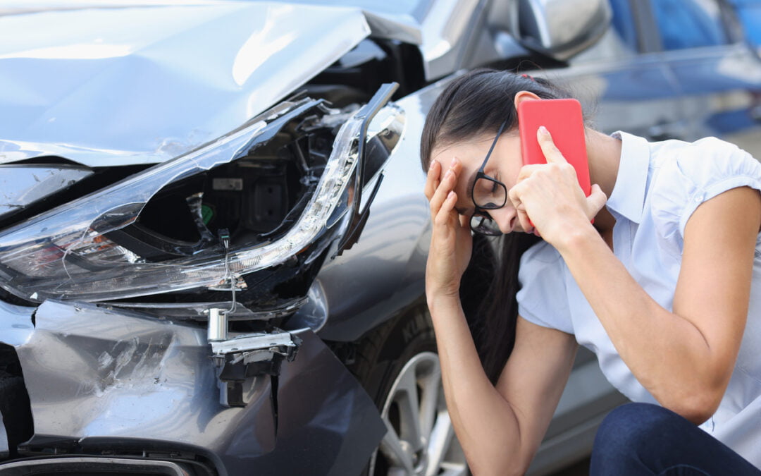 Third-party liability insurance - Sad woman talking on cell phone near wrecked car. Female driver concept