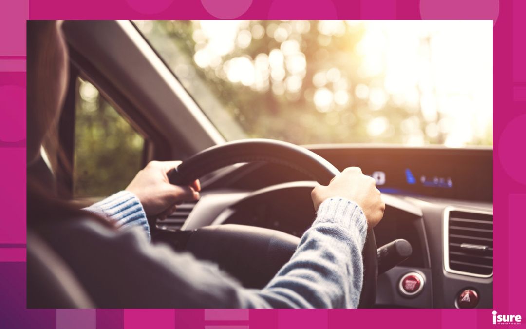 driving myths - over the shoulder shot of a woman driving with both hands on the steering wheel on a sunny day