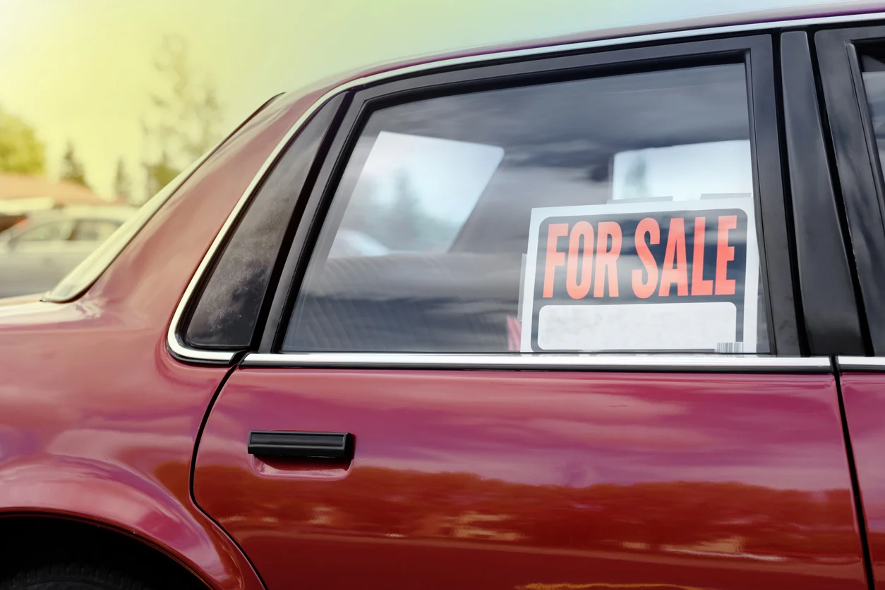 buying used vehicles - shiny car for sale in summer weather, parked with a red vibrant color exterior.