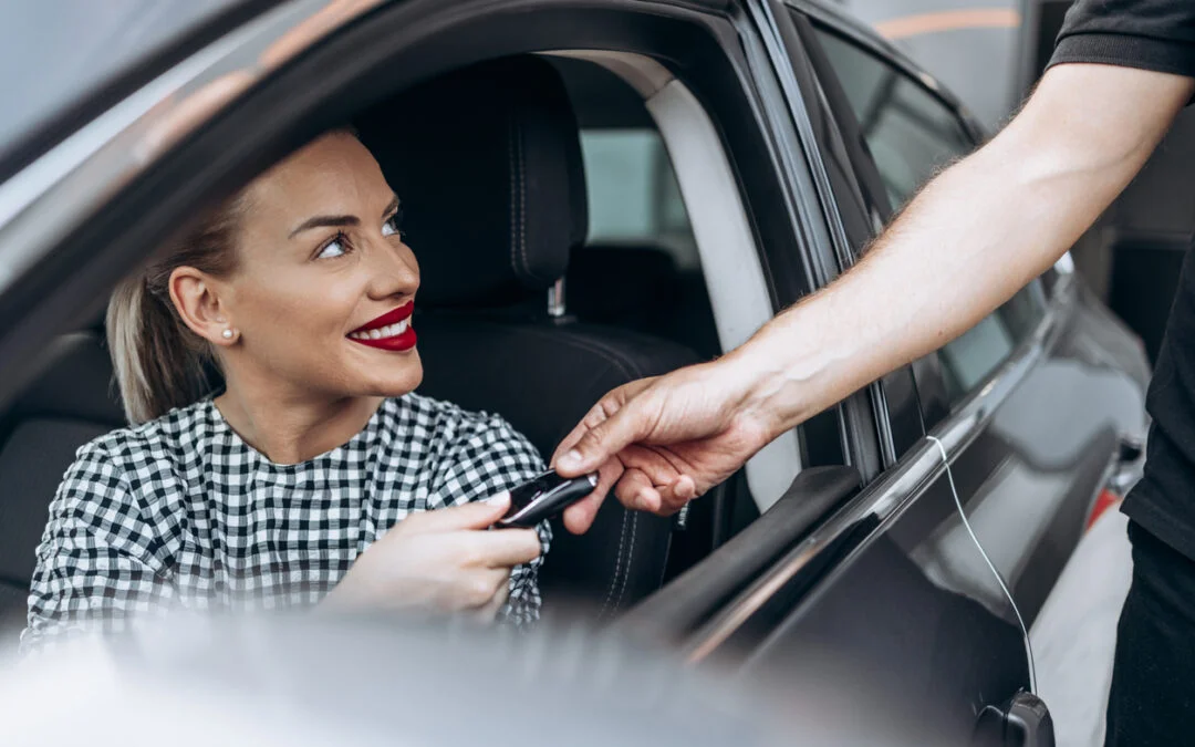 out-of-province vehicle - Satisfied and smiled female buyer sitting in her new car. She is smiling, looking at seller through open window while taking car keys from him