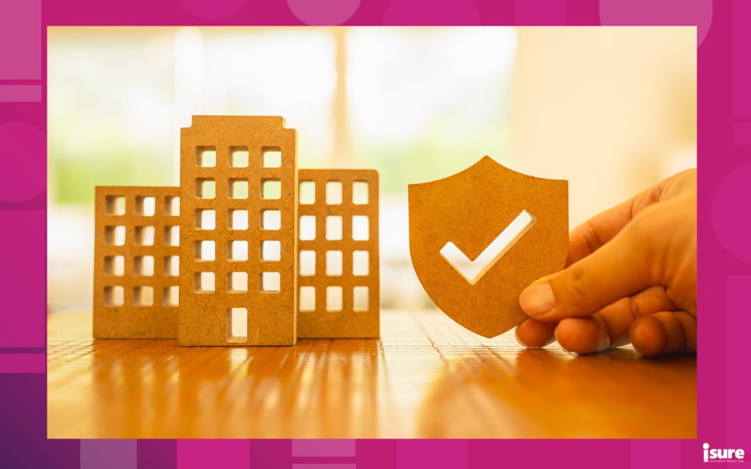A cutout of a commercial building and held beside it a hand holding a shield with a checkmark showing business insurance costs.