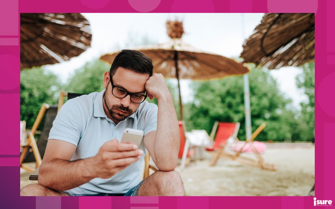 protect your home from theft while on vacation - Annoyed man on the beach looking at the mobile screen.