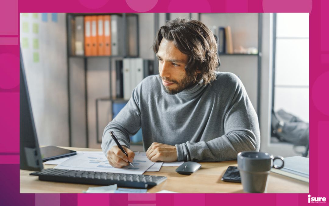 Man working from home on his desktop computer with a pen in his hand.