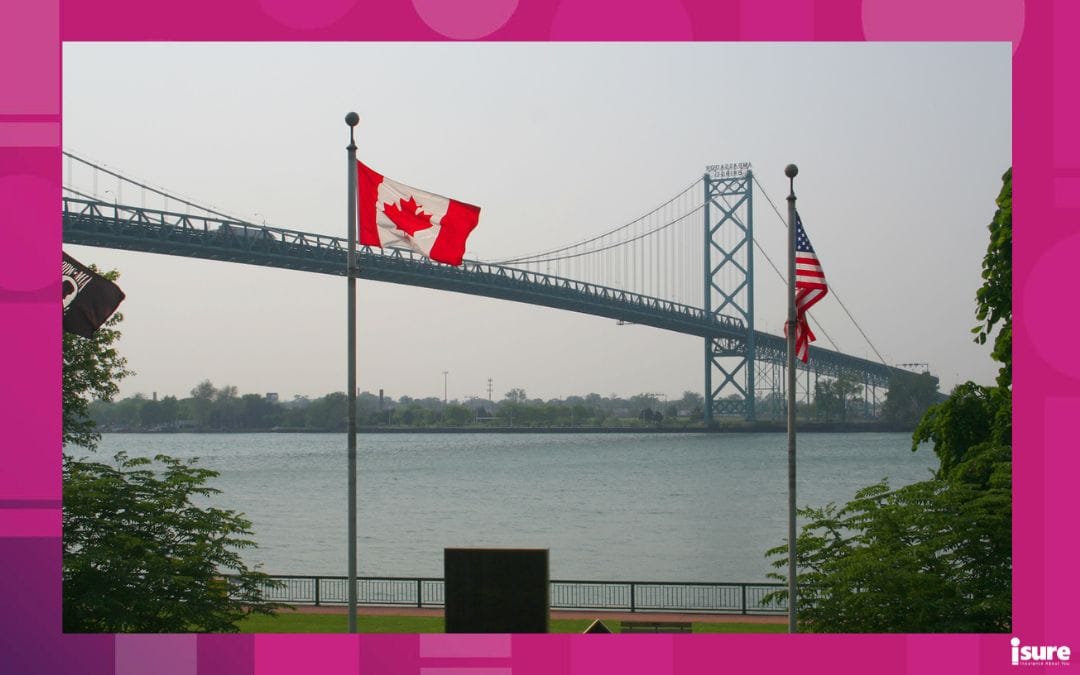 u.s. tariffs - A Canadian and American flag waving in the wind in front of the Ambassador bridge in Windsor, ON.