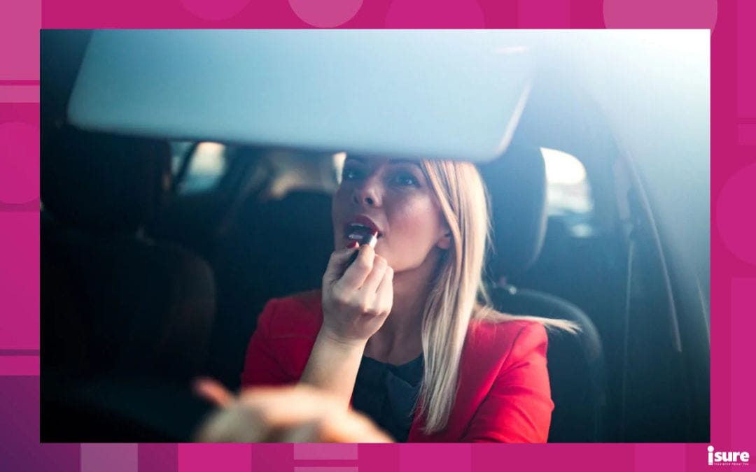Woman putting a red lipstick while sitting in a car -one of many penalties for distracted driving