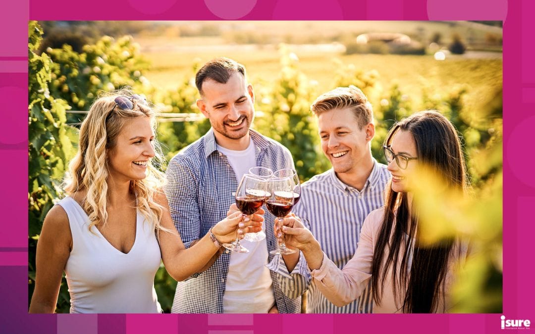 A group of four young adults smiling outdoors and drinking red wine.