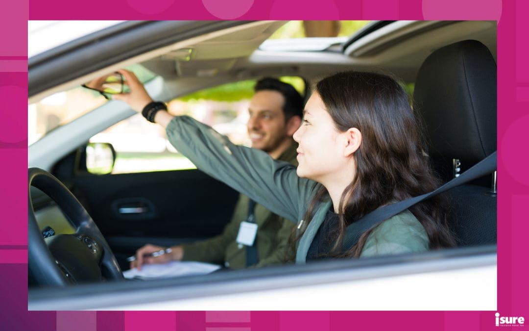 Adorable teenage girl adjusting the rear view mirror in the car during her driving practice with a good-looking male instructor - driving school