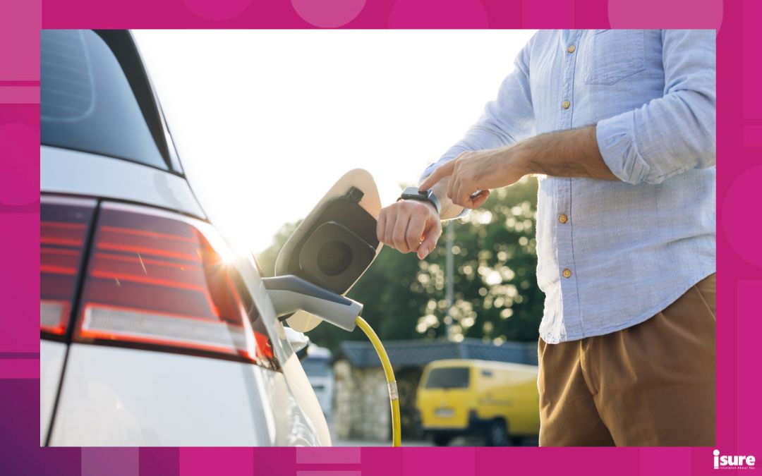 Unrecognizable businessman plugging in charging cable to electric car. Male hand inserts power connector into EV car and charges batteries, uses smartwatch for activates start charging