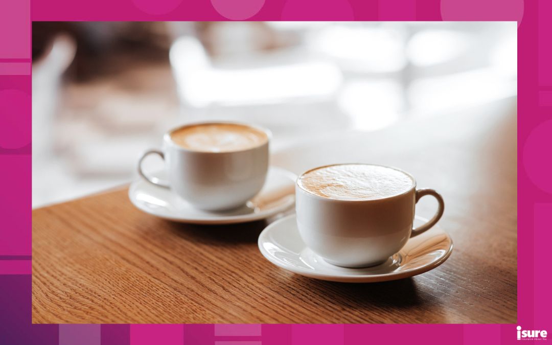 Two lattes sitting on the table of a cafe.