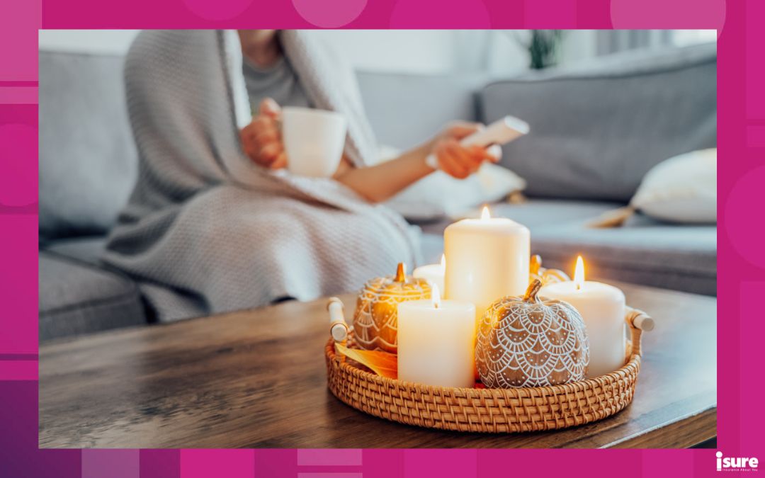 Focus on autumn fall cozy mood decor composition with a blurred woman covered plaid selecting movie with remote controller and drinking tea on the sofa. fall movie night party at home. Cozy relaxing time
