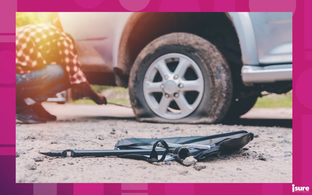 how to change a flat tire - photo of a driver changing a flat with a tire jack at the side of the road