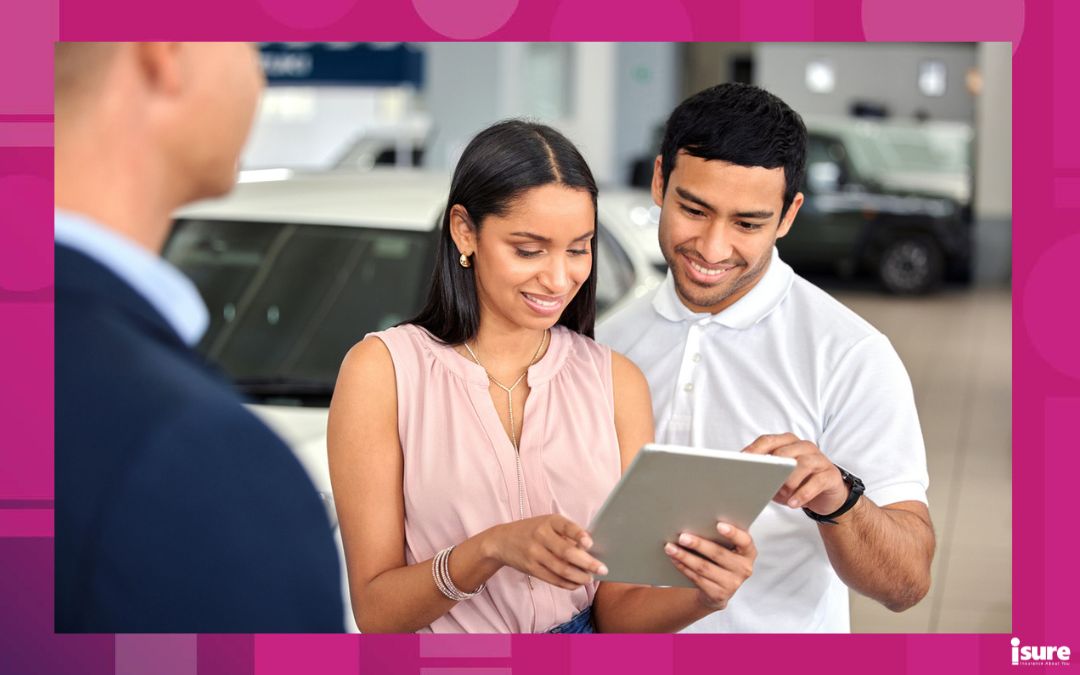 registering for auto insurance in a new province - young couple looking at an ipad in a car dealership purchasing a new car