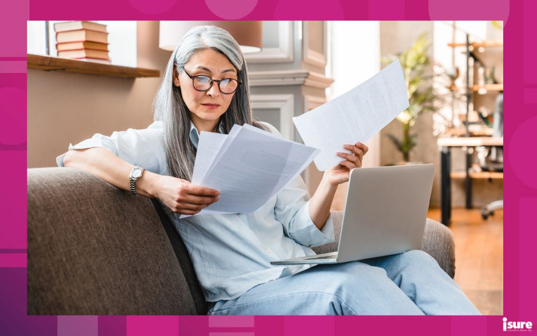 Busy attractive mature businesswoman working at home with laptop, reviewing what her home insurance policy doesn't cover