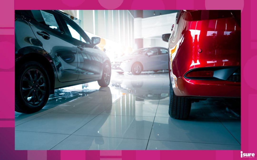 A modern Canadian car dealership showroom featuring new red and grey vehicles on a polished floor, illustrating the best time to buy a car in Canada.
