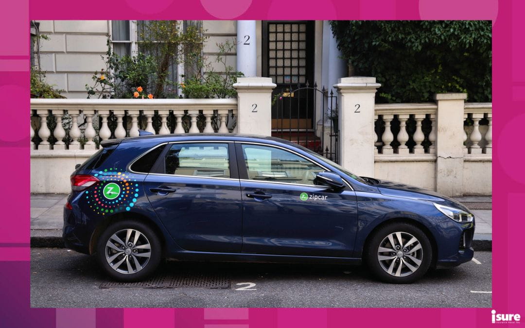 A blue car with Zipcar branding parked on the side of the road. Zipcar is one of the most popular companies when it comes to car-sharing services.
